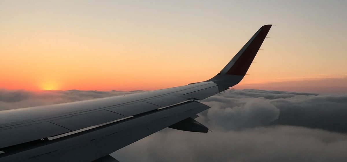 Airplane wing above the clouds at sunset